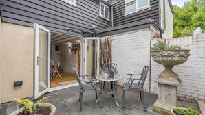 An open patio with a table and chairs, a potted plant, and a decorative urn. - 2 Bed in Peasmarsh (oc-s33528) (Peasmarsh)