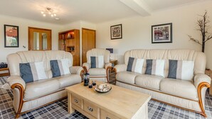 A living room with two sofas, a coffee table, and framed pictures on the wall. - 3 Bed in Aberdyfi (oc-54035) (Pennal)