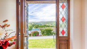 A doorway leading to a grassy area with a view of a house and hills in the distance. - 3 Bed in Aberdyfi (oc-54035) (Pennal)