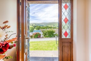 A doorway leading to a grassy area with a view of a house and hills in the distance. - 3 Bed in Aberdyfi (oc-54035) (Pennal)