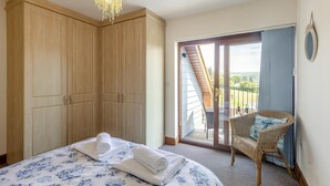 A bedroom with a bed, a wardrobe, a balcony with a chair, and a view of the outdoors. - 3 Bed in Aberdyfi (oc-54035) (Pennal)