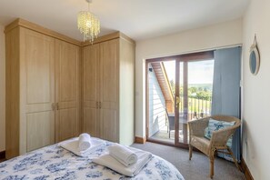 A bedroom with a bed, a wardrobe, a balcony with a chair, and a view of the outdoors. - 3 Bed in Aberdyfi (oc-54035) (Pennal)