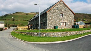 A stone building with a sloped roof, a small window, and a door. - 3 Bed in Aberdyfi (oc-54035) (Pennal)
