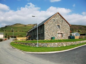 A stone building with a sloped roof, a small window, and a door. - 3 Bed in Aberdyfi (oc-54035) (Pennal)
