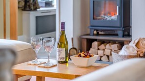 Un salon chaleureux avec une cheminée, une bouteille de vin et deux verres posés sur une table en bois.