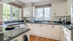Une cuisine moderne avec des meubles blancs, un plan de travail noir et une fenêtre donnant sur un jardin.