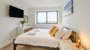 Una camera da letto con un letto, un comodino, una TV, una finestra e un quadro appeso al muro.