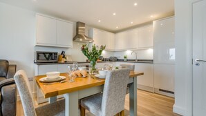 Una cucina moderna con mobili bianchi, un tavolo da pranzo in legno e sedie rivestite di grigio.