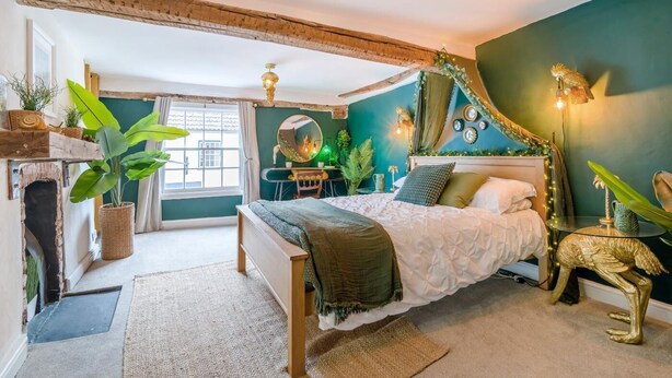 Ein Schlafzimmer mit einem Bett, einem Schreibtisch, einem Spiegel und einem Kamin.