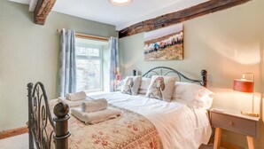 A bedroom with a bed, a nightstand, a lamp, a window with curtains, and a painting on the wall. - 3 Bed in Askrigg (oc-ds1035) (Askrigg)