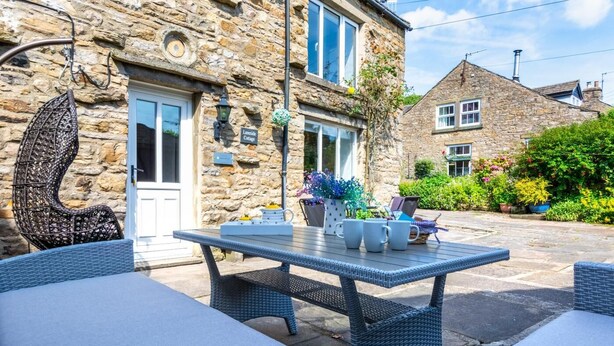 A stone cottage with a patio, wicker furniture, and potted plants. - 3 Bed in Askrigg (oc-ds1035) (Askrigg)
