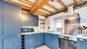 A modern kitchen with blue cabinets, a microwave, a coffee maker, and a large window. - 3 Bed in Askrigg (oc-ds1035) (Askrigg)