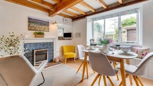 A dining area with a fireplace, a yellow chair, and a table set for two with wine glasses. - 3 Bed in Askrigg (oc-ds1035) (Askrigg)