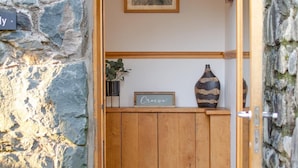Eine Fassade aus Stein mit einer Holztür, einem Blumentopf und einem gerahmten Bild an der Wand.