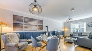 Un salon moderne avec un coin repas, agrémenté d’une cheminée, de meubles contemporains et d’œuvres d’art aux murs.