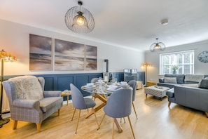 Ein modernes Wohnzimmer mit Essbereich, inklusive Kamin, zeitgenössischer Möbel und Kunstwerken an den Wänden.