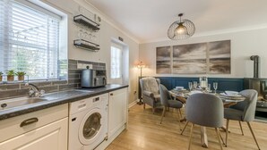 Une cuisine moderne équipée d’un lave-linge, d’une machine à café et d’un coin repas avec une table et des chaises.