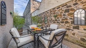 Un espace extérieur aménagé avec des murs en pierre, comprenant une table, des chaises et un petit jardin.