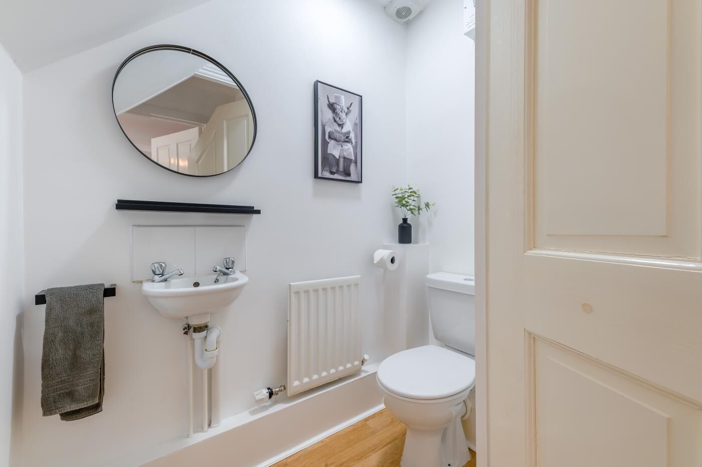 Une salle de bain avec un lavabo blanc, un miroir, des toilettes et un radiateur.