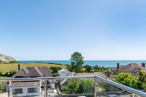 Un quartier résidentiel situé sur la côte, avec des maisons, un ciel dégagé et une vue sur la mer.