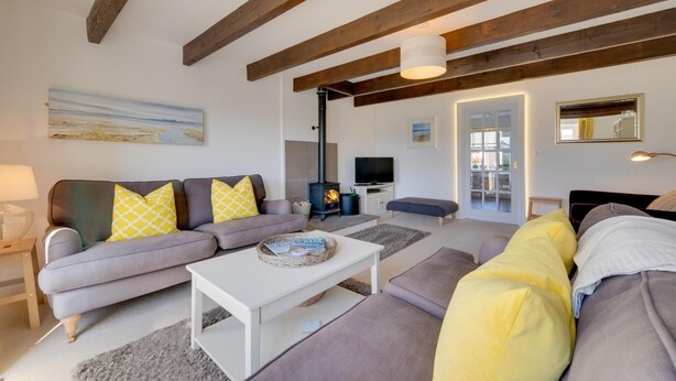 A living room with a sofa, a coffee table, a television, and a fireplace. - 3 Bed in Beadnell (oc-566714) (Swinhoe)