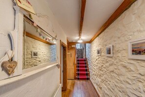 Ein schmaler Gang mit Steinwänden, Holzbalken und einer roten Teppichstufen Treppe, die zu einer Tür mit der Aufschrift 'HOME' führt.