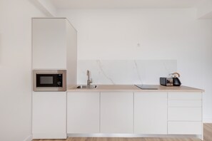 Una cocina moderna con microondas integrado, un fregadero y una tostadora sobre la encimera.