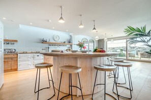 Une cuisine moderne dotée d’un îlot central, de tabourets de bar et d’une grande fenêtre offrant une vue dégagée.