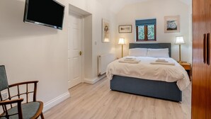 Ein Schlafzimmer mit einem Bett, Nachttischlampen, einem Fernseher und einem Sessel.