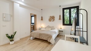 Une chambre à coucher moderne avec un lit, des tables de chevet, un bureau et une fenêtre.