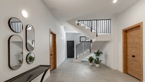 Un intérieur moderne avec un escalier, une console et des miroirs fixés au mur.