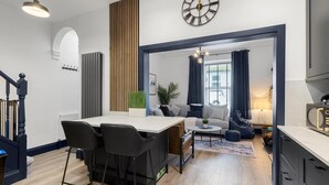 A modern kitchen with a dining area, a living room with a sofa and a coffee table, and a staircase. - 4 Bed in Brixham (oc-h33642) (Brixham)