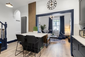 Eine moderne Küche mit Essbereich, ein Wohnzimmer mit Sofa und Couchtisch sowie eine Treppe.