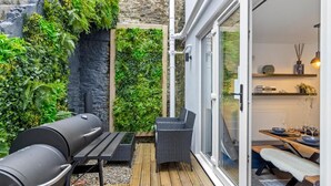 A patio with a grill, wicker chairs, and a table. - 4 Bed in Brixham (oc-h33642) (Brixham)
