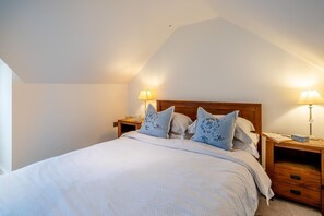 A bedroom with a single bed, two bedside tables, and two wall-mounted lamps.