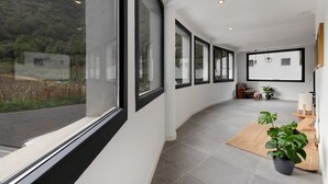 A modern interior with large windows, a curved floor, and a potted plant. - Holiday Apartment '4' with Mountain Views, Shared Terrace and Garden (Moya)
