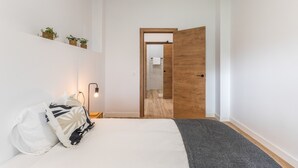 A bedroom with a bed, bedside table, lamp, and a door leading to a bathroom. - Vacation Apartment '5' with Mountain View, Shared Terrace and Shared Garden (Moya)