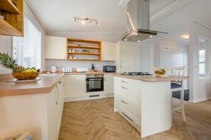 A modern kitchen with white cabinetry, a central island, a microwave, an oven, and a gas stove.