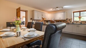 Una cocina moderna con armarios blancos, un comedor con mesa de madera dispuesta para cuatro personas, y un ventanal que proporciona luz natural.