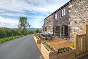 A stone building with a wooden deck and outdoor seating area. - 3 Bed in Machynlleth (oc-21015) (Machynlleth)