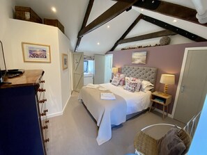 A bedroom with a bed, bedside tables, a desk, a chair, and a window.
