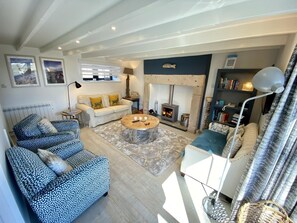 A living room with a fireplace, sofas, a coffee table, and a bookshelf.