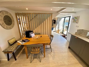 Une cuisine moderne avec une table à manger en bois, des chaises et une grande horloge au mur.