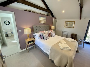 Une chambre à coucher avec un lit, des lampes de chevet, une table de chevet, une chaise et une fenêtre.