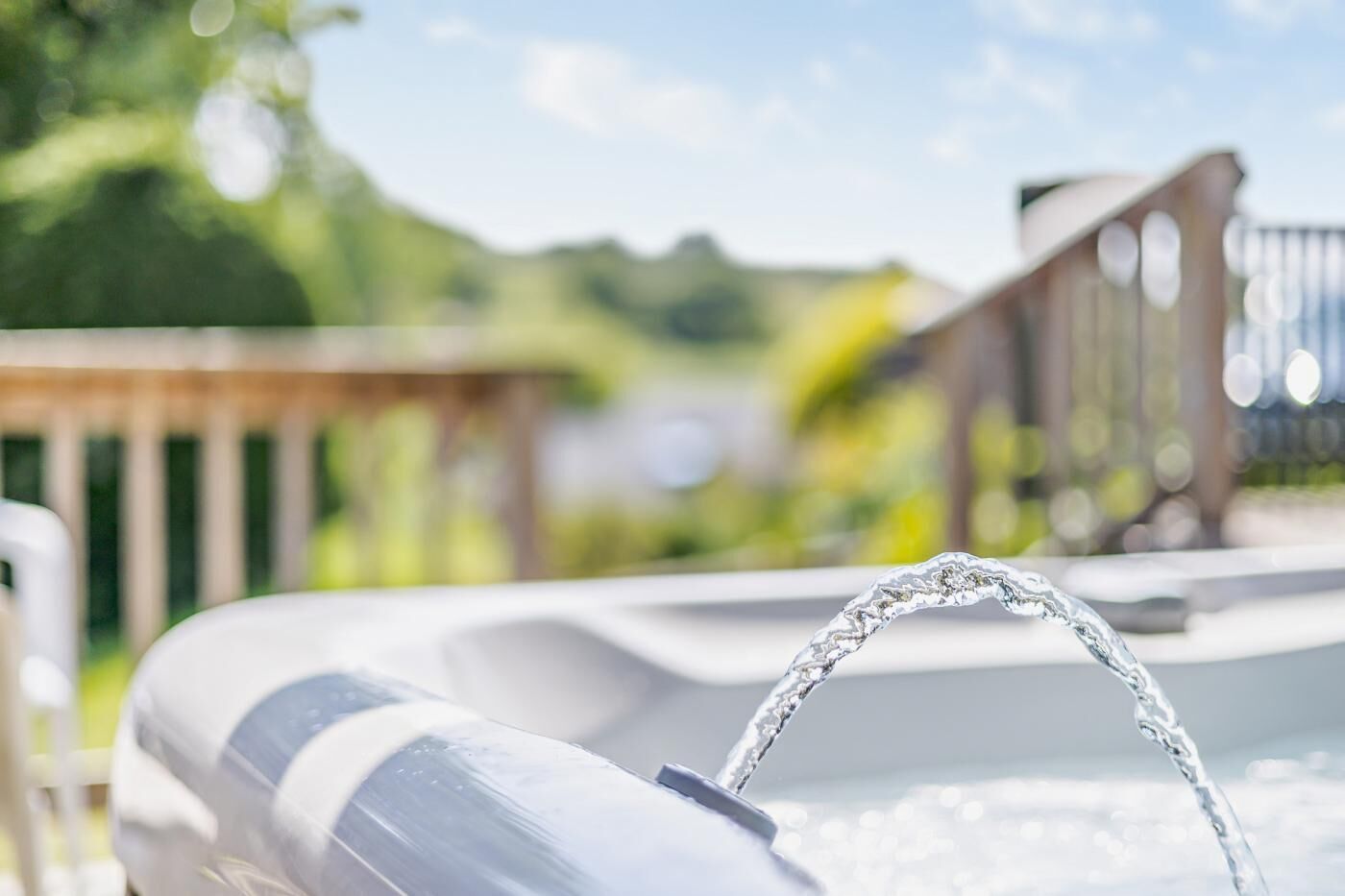 A hot tub with a wooden deck and a view of a lake.