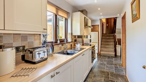 A modern kitchen with white cabinets, a wooden countertop, and a built-in stove. - 2 Bed in Aberystwyth (oc-99869) (Pontarfynach)
