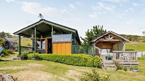 A rustic cabin with a porch and a small wooden structure. - 2 Bed in Aberystwyth (oc-99869) (Pontarfynach)