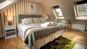 Een slaapkamer met een groot bed, nachtkastje, stoel, radiator en raam.