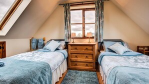 Ein Schlafzimmer mit zwei Betten, einem hölzernen Schminktisch und einem Oberlicht.