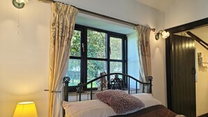 Un dormitorio con cama, una ventana con cortinas, una lámpara y una puerta.
